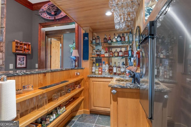 indoor bar featuring stainless steel fridge, stone finish floors, and crown molding