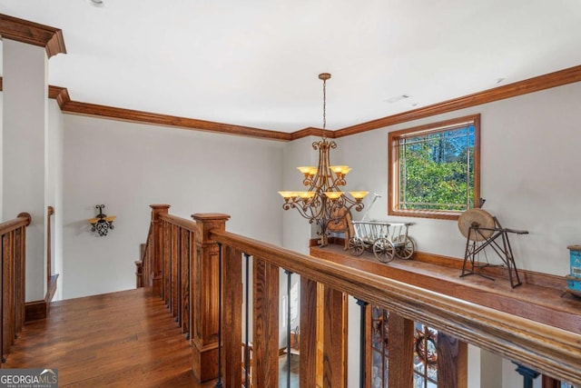 corridor with a chandelier, an upstairs landing, wood finished floors, and crown molding