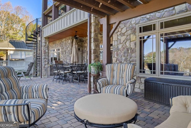 view of patio featuring outdoor dining area, stairway, ceiling fan, and a balcony