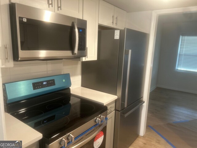 5611 Executive Way, Norcross, GA 30071 - kitchen featuring light wood-style floors, light countertops, stainless steel appliances, white cabinetry, and backsplash
