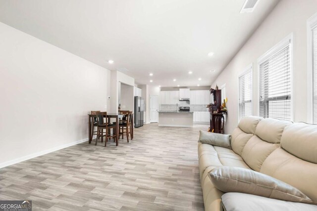 living area featuring baseboards, light wood-style floors, and recessed lighting