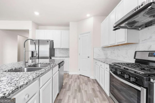kitchen with white cabinets, a sink, stainless steel appliances, and under cabinet range hood