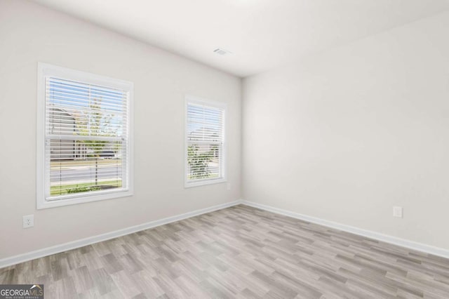 unfurnished room with baseboards, visible vents, and light wood-style flooring