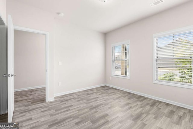 spare room with baseboards, light wood-style flooring, and visible vents