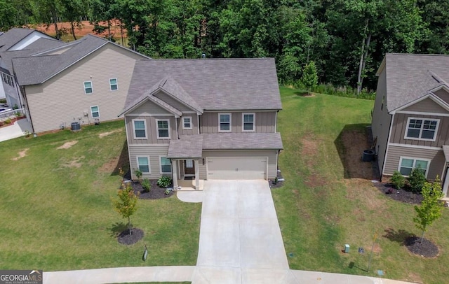 view of front of property with concrete driveway, an attached garage, board and batten siding, a front lawn, and central AC