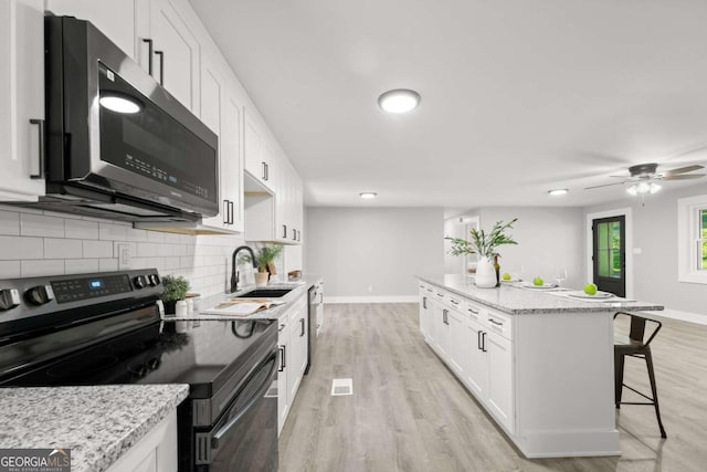 5198 Holly Springs Rd, Pendergrass, GA 30567 - kitchen featuring a kitchen breakfast bar, stainless steel appliances, a center island, backsplash, and white cabinets