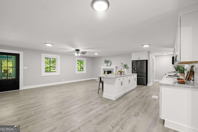 5198 Holly Springs Rd, Pendergrass, GA 30567 - kitchen with white cabinets, a kitchen island, black fridge, open floor plan, and a kitchen breakfast bar