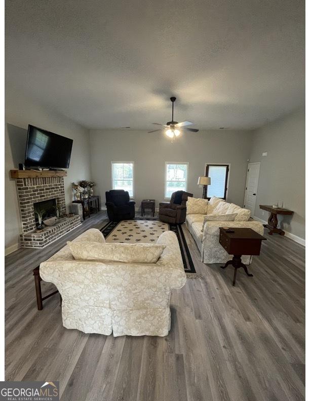 4529 Jersey Covington Rd, Covington, GA 30014 - living area featuring wood finished floors, a ceiling fan, a fireplace, and baseboards