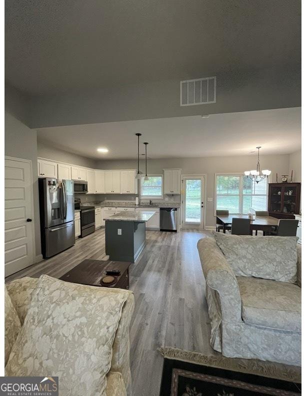4529 Jersey Covington Rd, Covington, GA 30014 - kitchen featuring stainless steel appliances, white cabinetry, wood finished floors, a chandelier, and recessed lighting