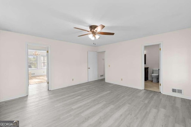 interior space featuring ceiling fan with notable chandelier, visible vents, baseboards, and light wood-type flooring