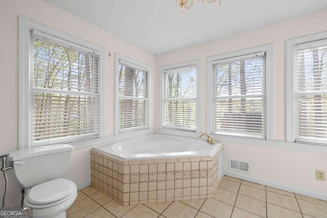 full bathroom with tile patterned floors, plenty of natural light, tiled tub, and visible vents
