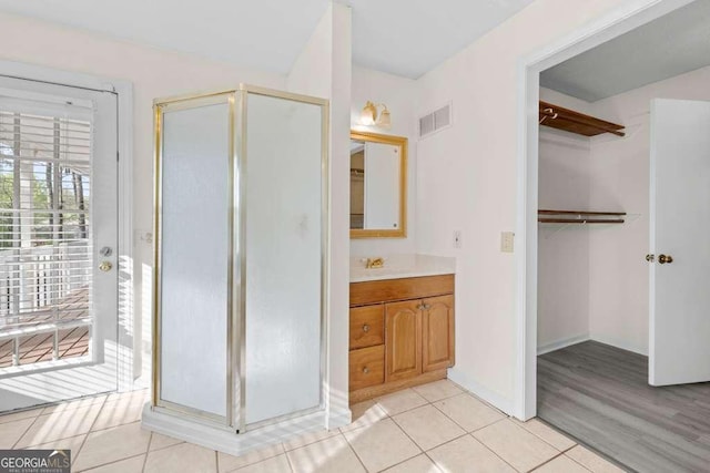full bath featuring tile patterned flooring, vanity, baseboards, a stall shower, and visible vents
