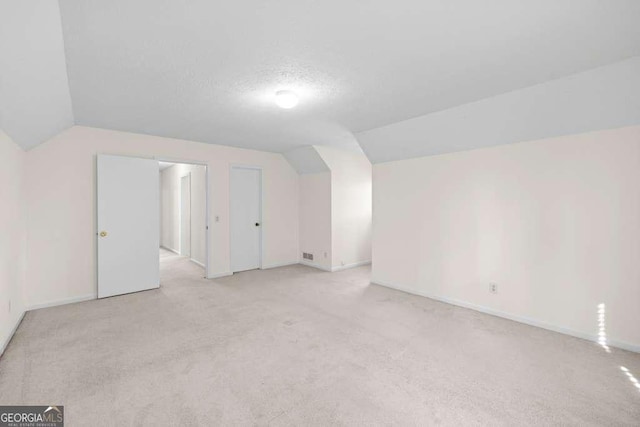 bonus room with light carpet, baseboards, vaulted ceiling, and a textured ceiling