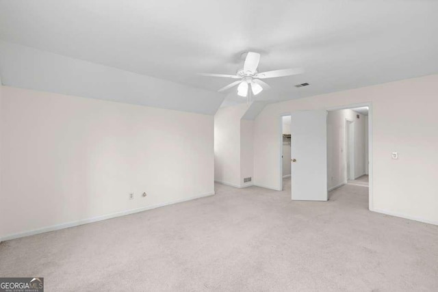 interior space with vaulted ceiling, baseboards, visible vents, a ceiling fan, and light carpet