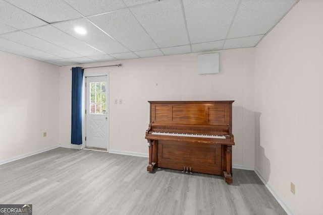 living area with baseboards, wood finished floors, and a paneled ceiling