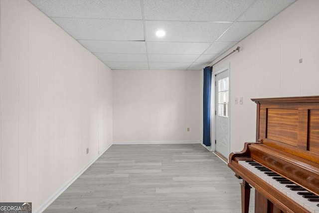 interior space featuring a paneled ceiling, baseboards, and wood finished floors