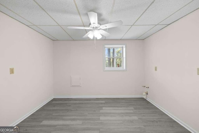 unfurnished room with baseboards, wood finished floors, ceiling fan, and a paneled ceiling