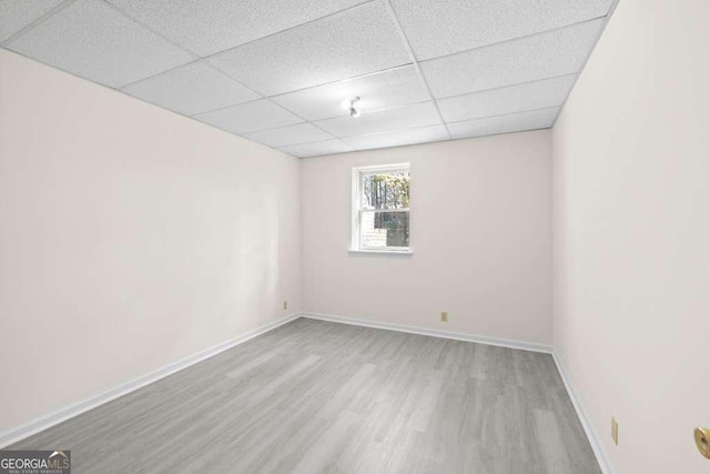 spare room with baseboards, wood finished floors, and a paneled ceiling