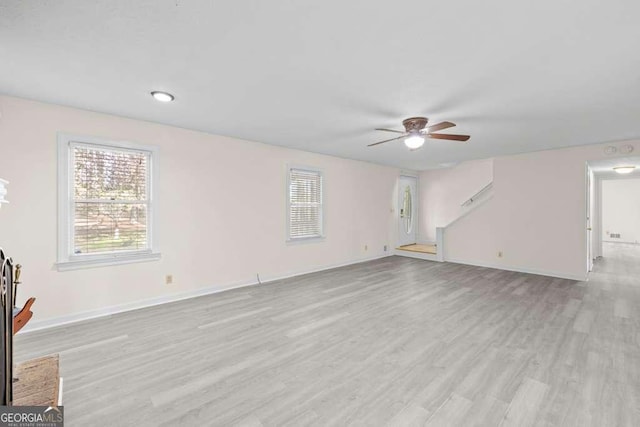 unfurnished living room with baseboards, light wood-type flooring, and a ceiling fan