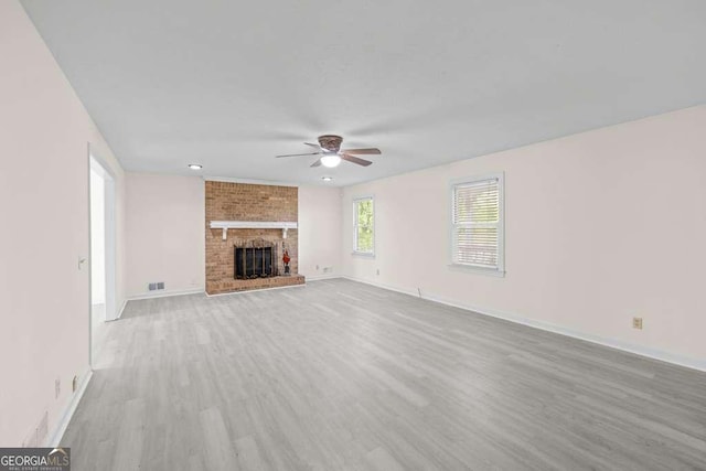 unfurnished living room with a fireplace, baseboards, ceiling fan, and wood finished floors