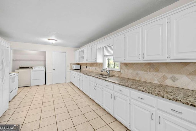 kitchen featuring white cabinets, a sink, washer and clothes dryer, and tasteful backsplash