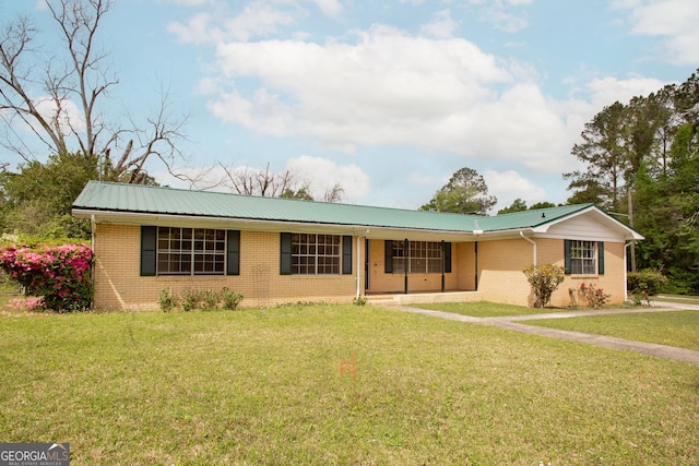 ranch-style home with brick siding, a front yard, and metal roof