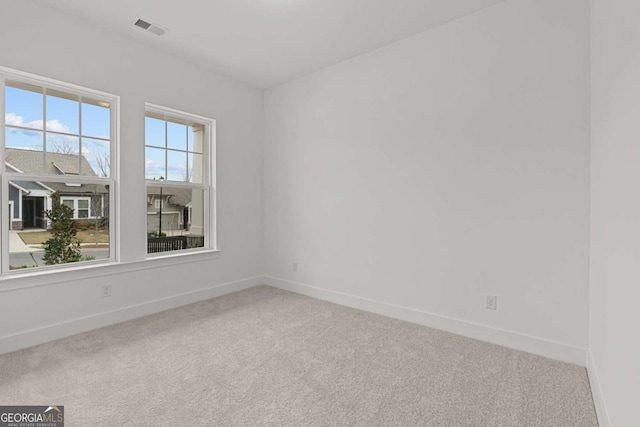 carpeted empty room featuring baseboards and visible vents