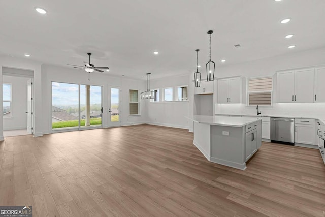 kitchen with light wood-type flooring, a ceiling fan, a kitchen island, and stainless steel dishwasher