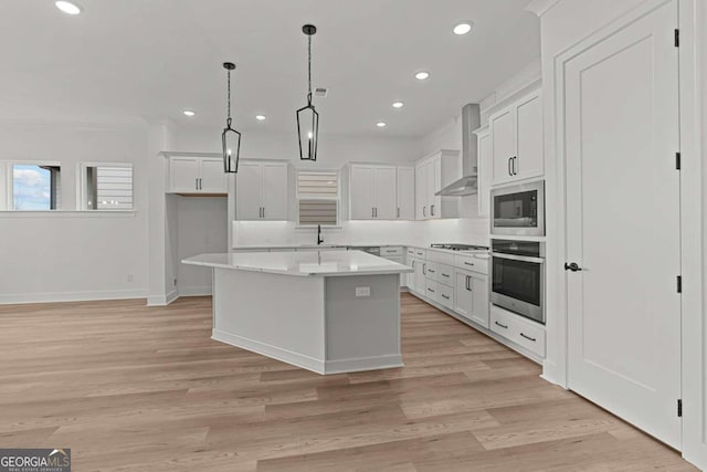 kitchen with oven, gas cooktop, a center island, built in microwave, and wall chimney exhaust hood