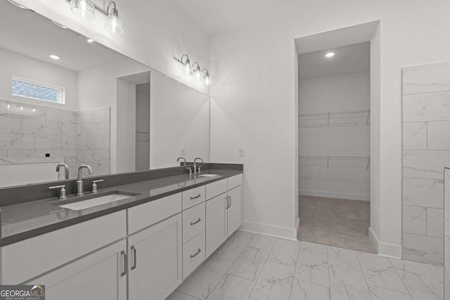 bathroom with marble finish floor, a walk in closet, and a sink