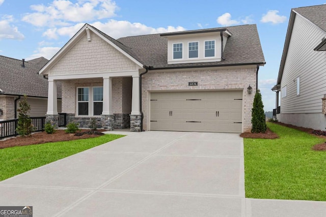 craftsman-style house featuring covered porch, concrete driveway, brick siding, a front lawn, and a garage