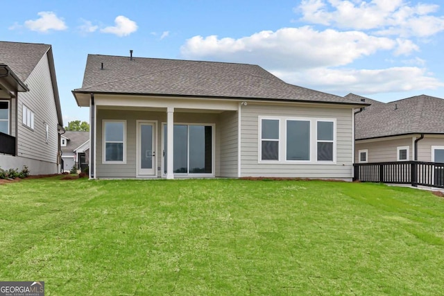back of property featuring roof with shingles and a yard