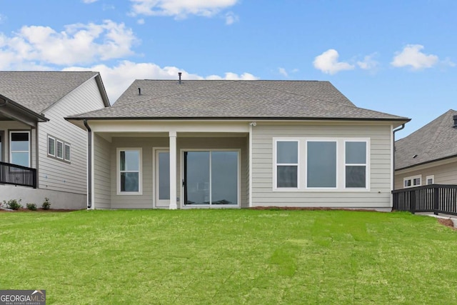 rear view of property featuring a shingled roof and a yard
