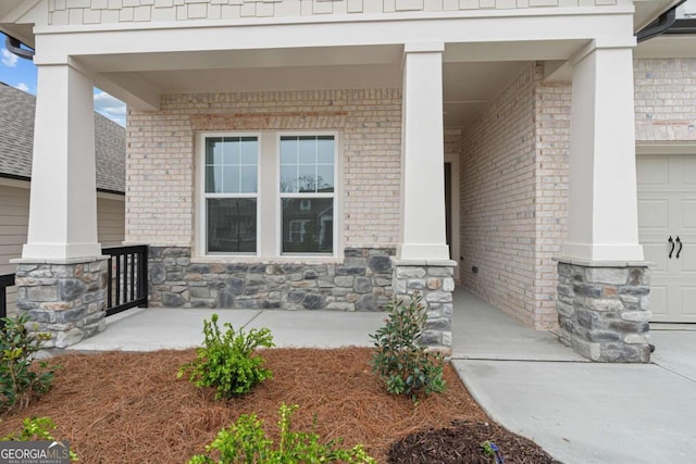 entrance to property with covered porch, stone siding, and brick siding