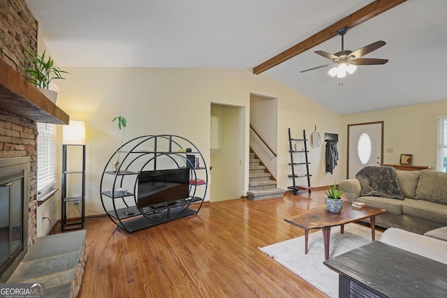3916 S Martin Way, Lithia Springs, GA 30122 - living room with ceiling fan, a brick fireplace, wood finished floors, vaulted ceiling with beams, and stairs