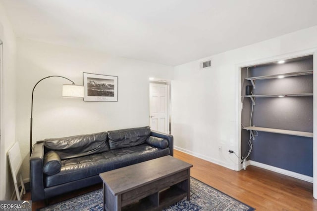 living room featuring visible vents, baseboards, and wood finished floors