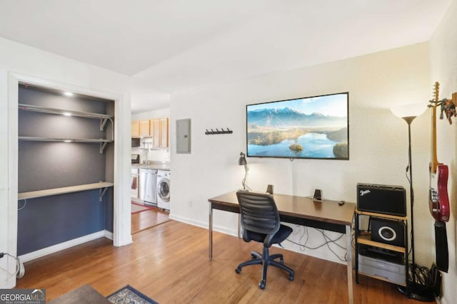 office space featuring electric panel, washer / clothes dryer, baseboards, and wood finished floors