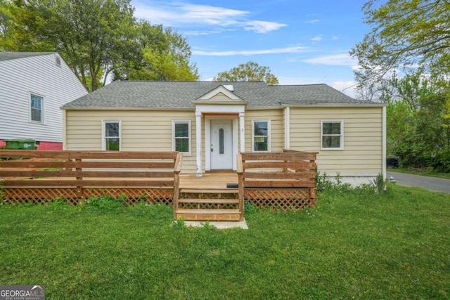 bungalow-style home featuring a front lawn, a deck, and roof with shingles