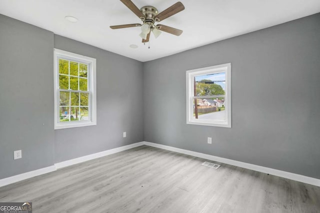 unfurnished room featuring baseboards, visible vents, a ceiling fan, and wood finished floors