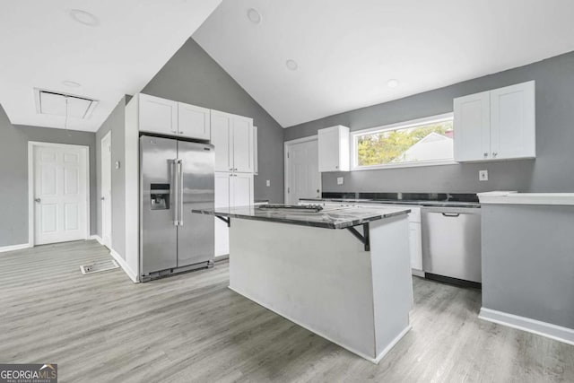 kitchen featuring white cabinetry, vaulted ceiling, a kitchen island, light wood finished floors, and appliances with stainless steel finishes
