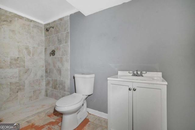 full bathroom featuring toilet, vanity, baseboards, and tiled shower