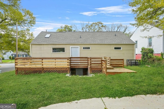 rear view of property with a shingled roof, a yard, and a wooden deck