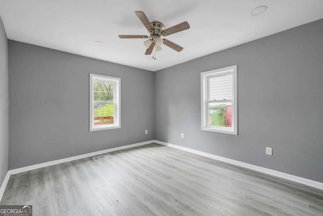 spare room featuring baseboards, visible vents, wood finished floors, and a ceiling fan