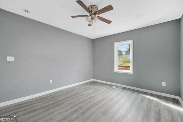 unfurnished room with wood finished floors, visible vents, baseboards, and ceiling fan