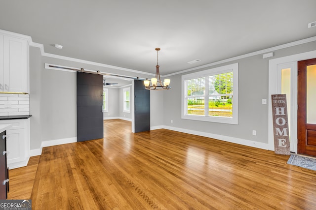 68 Hayes St, Toccoa, GA 30577 - unfurnished dining area with a barn door, light wood-style floors, baseboards, ornamental molding, and plenty of natural light