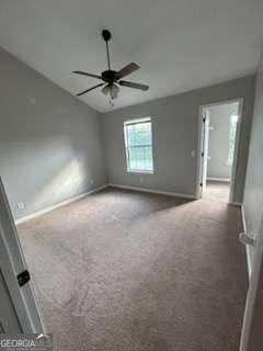 carpeted spare room featuring baseboards and a ceiling fan