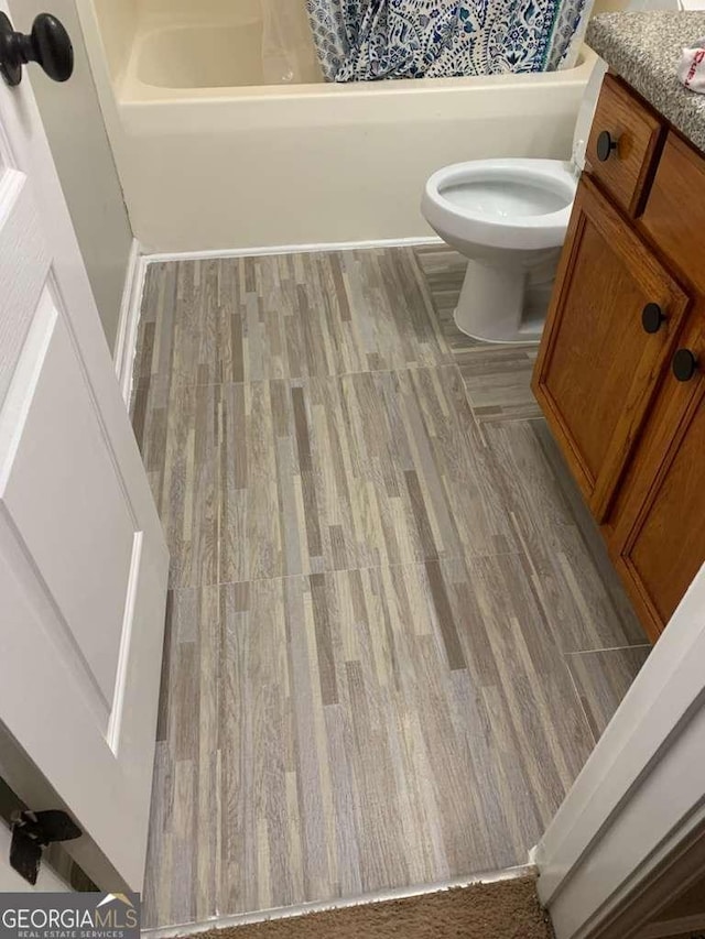 full bath with toilet, vanity,  shower combination, and wood finished floors