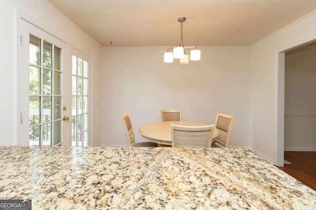 dining space with baseboards, a chandelier, and wood finished floors