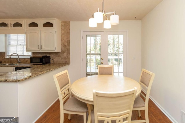 dining room featuring an inviting chandelier, french doors, baseboards, a textured ceiling, and dark wood-style floors