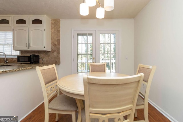 dining space with baseboards, dark wood-style floors, and a notable chandelier